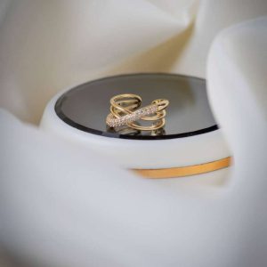 Anillo dorado de diseño cruzado y ajustable con incrustaciones de cristales brillantes.